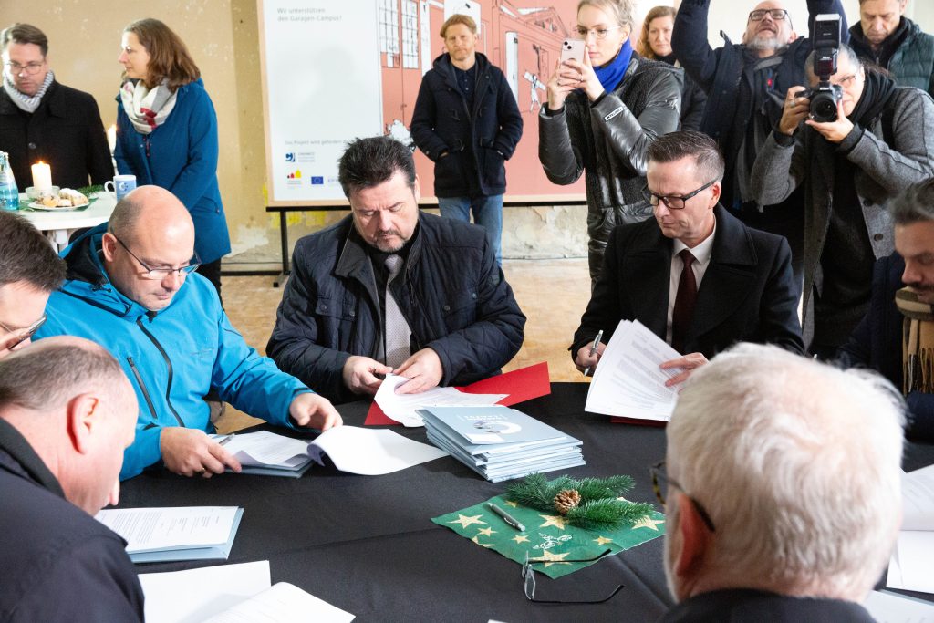 Jens Meiwald und die Geschäftsführenden der Unternehmen unterschreiben ihre Sponsoring-Verträge an einem runden Tisch. 
